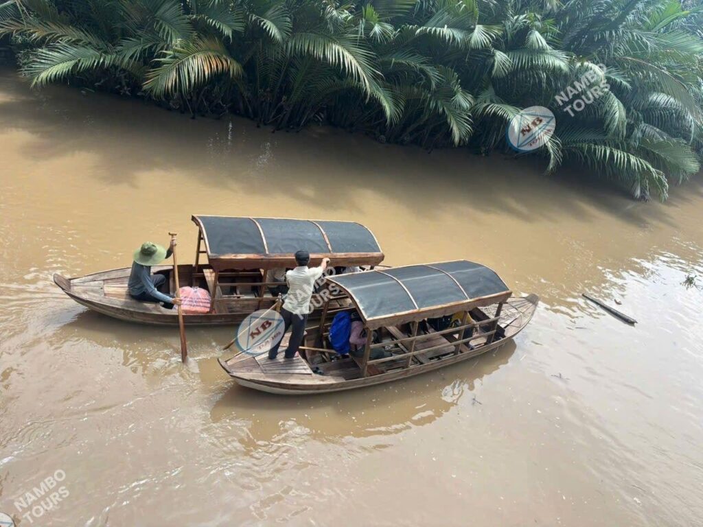 Ben Tre boat tour – local guide rowing a wooden sampan on a quiet water-coconut canal