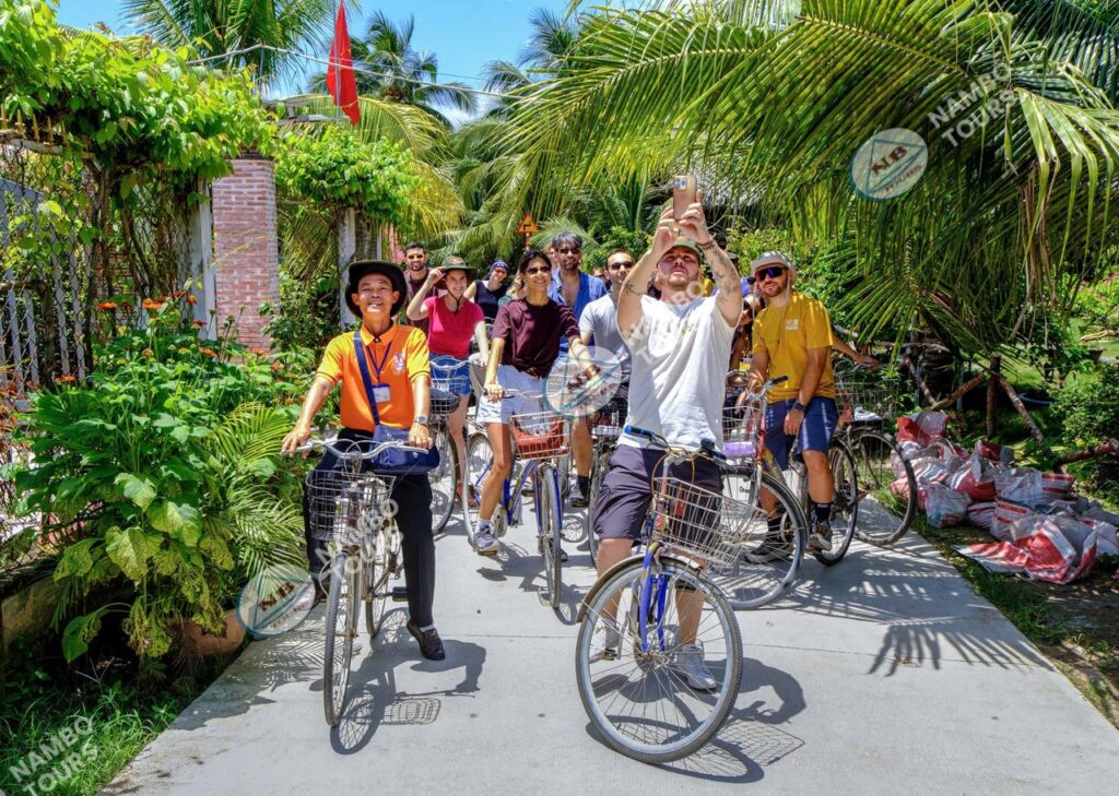Group of travellers cycling through a village on a Ben Tre tour