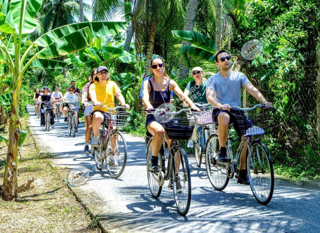 Nam Bo Tours guests cycling through a coconut village on a Ben Tre tour