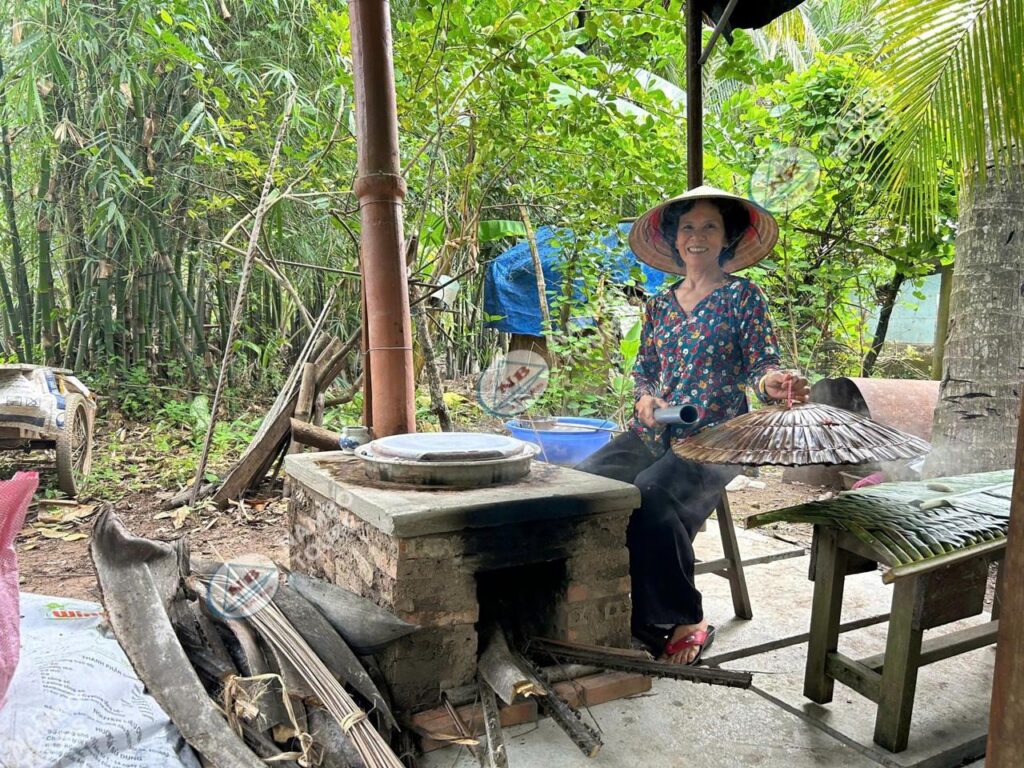 Guests making rice paper with a local family on a private Mekong Delta tour in Ben Tre